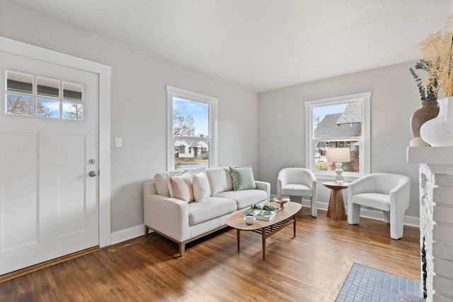 living area featuring a stone fireplace, wood finished floors, and baseboards