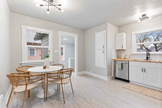 dining room featuring a notable chandelier, baseboards, and light wood finished floors