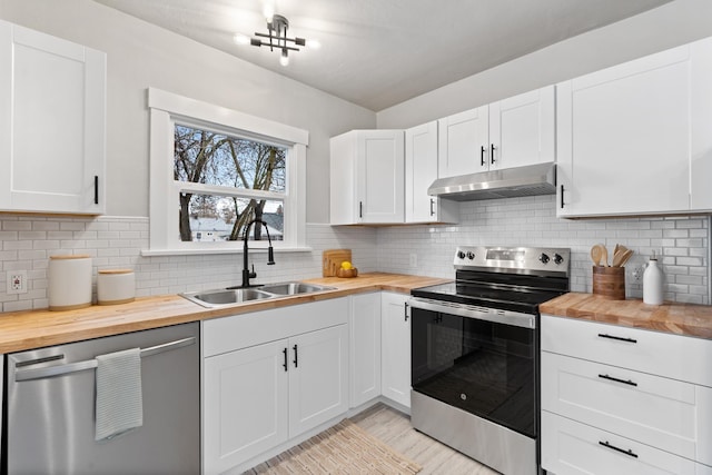 kitchen with under cabinet range hood, a sink, appliances with stainless steel finishes, white cabinets, and wooden counters