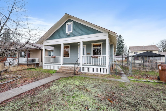 bungalow-style house featuring a gate, covered porch, and fence