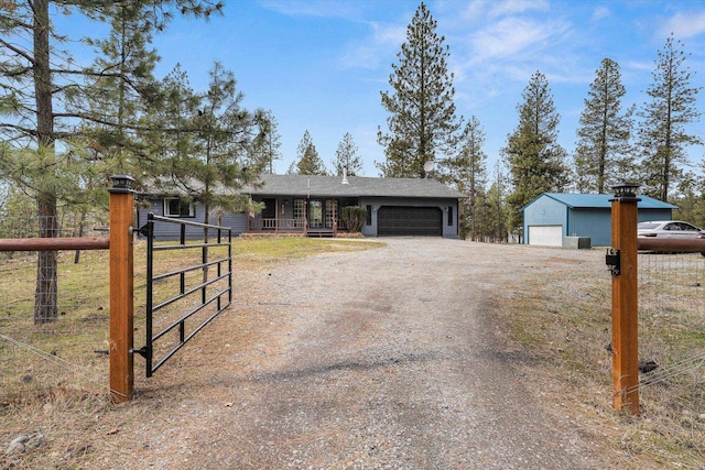 view of front of property featuring an attached garage, a gate, fence, and dirt driveway