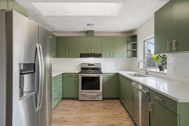 kitchen with green cabinetry, a sink, stainless steel appliances, extractor fan, and light wood-style floors