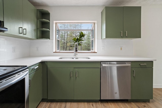 kitchen featuring a sink, light wood-style floors, stainless steel appliances, and green cabinetry