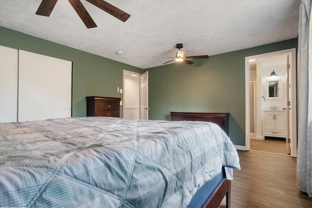 bedroom featuring a sink, a textured ceiling, wood finished floors, and ceiling fan