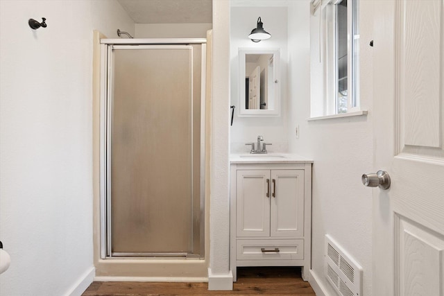 bathroom with vanity, wood finished floors, visible vents, baseboards, and a shower stall