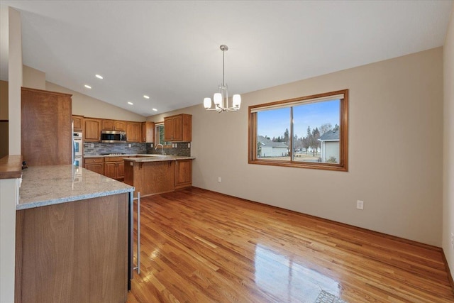 kitchen with a kitchen bar, brown cabinets, appliances with stainless steel finishes, and vaulted ceiling