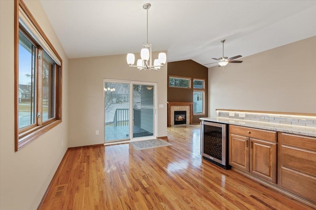 kitchen with a glass covered fireplace, plenty of natural light, beverage cooler, and light wood-type flooring