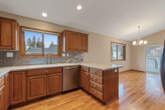 kitchen featuring a peninsula, a sink, vaulted ceiling, stainless steel dishwasher, and brown cabinets