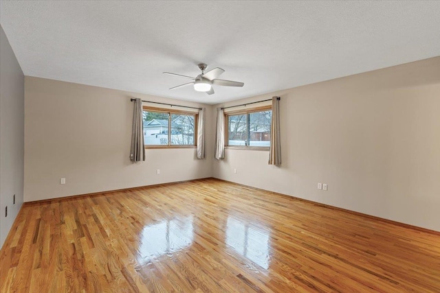 unfurnished room with light wood finished floors, baseboards, a textured ceiling, and a ceiling fan