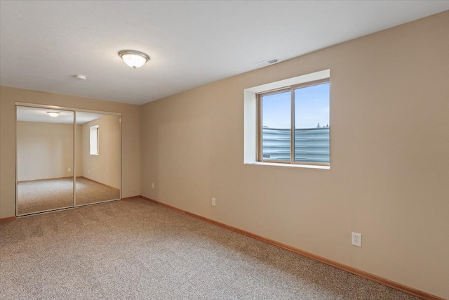 unfurnished bedroom with multiple windows, carpet, visible vents, and baseboards