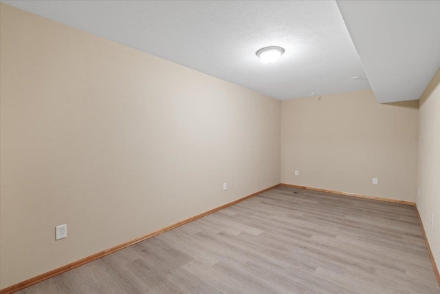 unfurnished room featuring baseboards, a textured ceiling, and light wood-style flooring