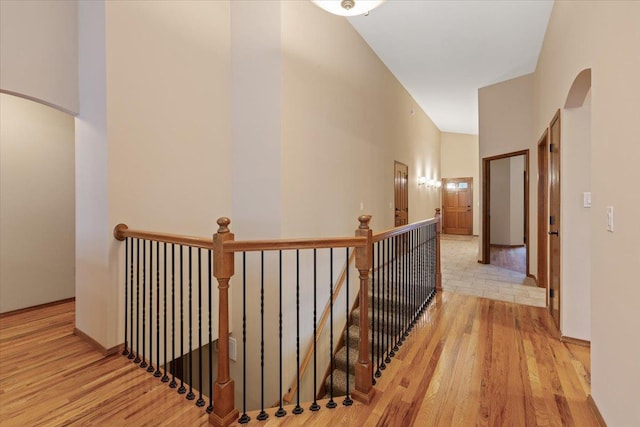 hallway with arched walkways, an upstairs landing, and wood finished floors