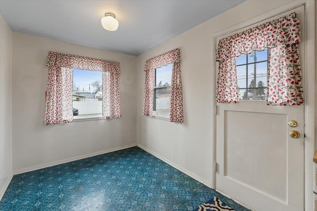 entrance foyer featuring dark floors, baseboards, and a wealth of natural light