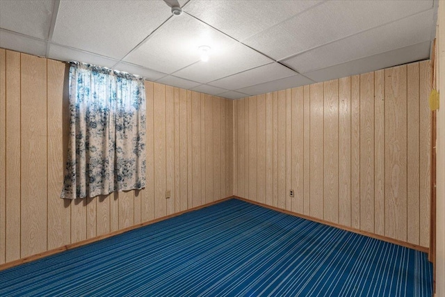 spare room with a drop ceiling and wooden walls