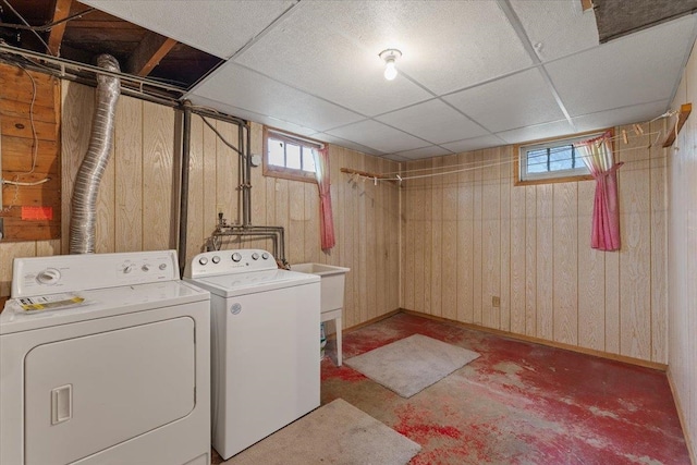 laundry area featuring laundry area, wood walls, baseboards, and separate washer and dryer