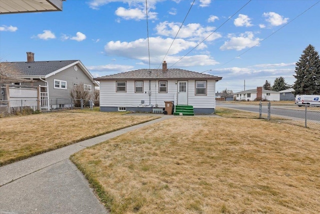 rear view of property featuring entry steps, a yard, and fence