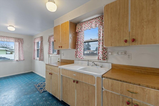 kitchen with a healthy amount of sunlight, light countertops, baseboards, and a sink