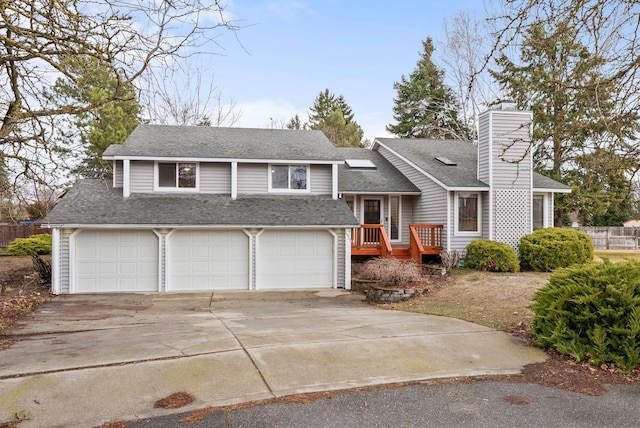 tri-level home with concrete driveway, fence, roof with shingles, and a chimney