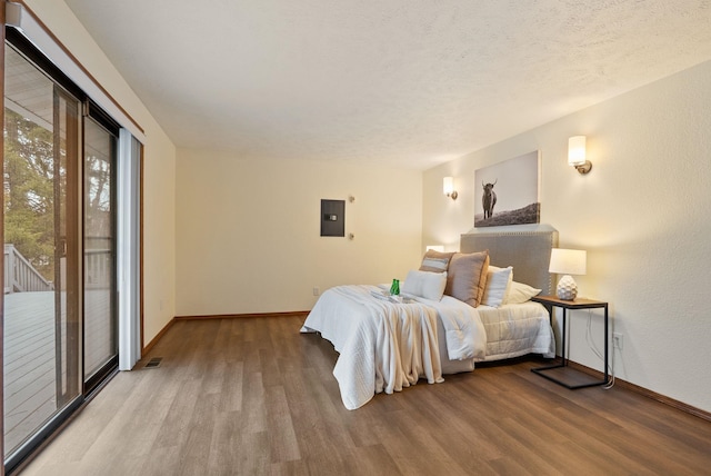 bedroom featuring access to exterior, baseboards, electric panel, and wood finished floors