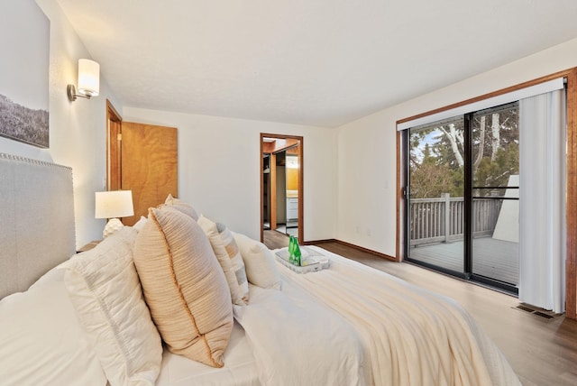 bedroom with visible vents, wood finished floors, baseboards, and access to exterior