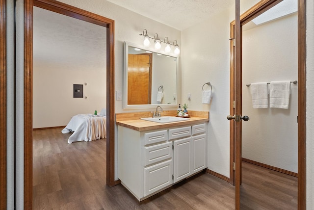 bathroom featuring a textured ceiling, wood finished floors, connected bathroom, baseboards, and vanity