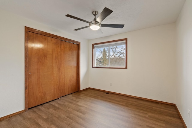 unfurnished bedroom featuring a closet, baseboards, ceiling fan, and light wood finished floors