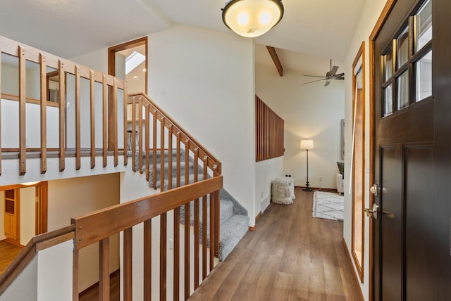 foyer entrance featuring wood finished floors, baseboards, lofted ceiling, ceiling fan, and stairs