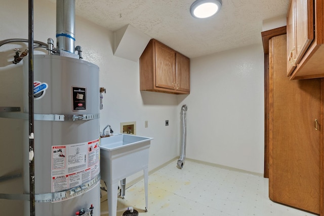 laundry area with strapped water heater, cabinet space, light floors, and a textured ceiling