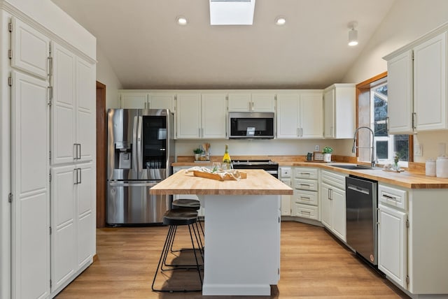 kitchen featuring stainless steel appliances, wooden counters, and lofted ceiling with skylight