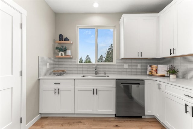 kitchen with a sink, light countertops, white cabinets, dishwasher, and backsplash