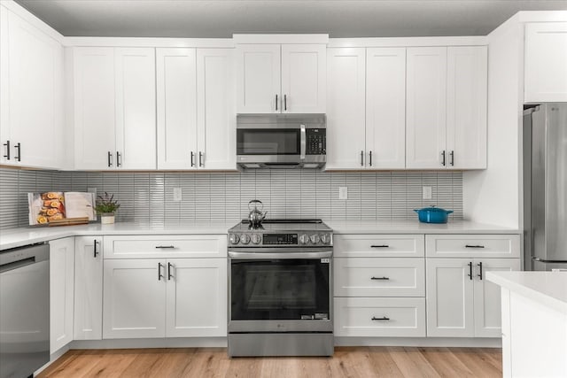 kitchen with light countertops, white cabinets, light wood-type flooring, and stainless steel appliances