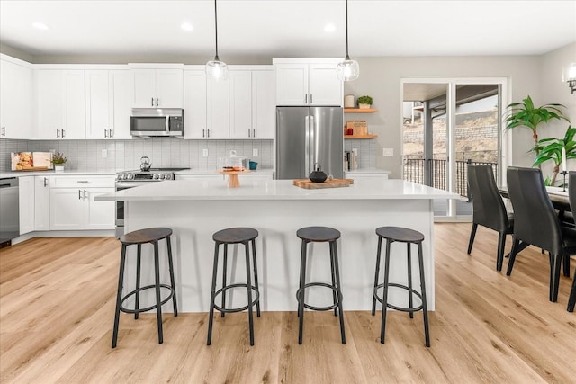 kitchen featuring a kitchen island, white cabinets, stainless steel appliances, and light countertops