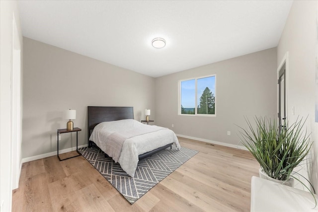 bedroom with light wood-type flooring and baseboards