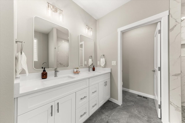 bathroom featuring double vanity, visible vents, baseboards, and a sink