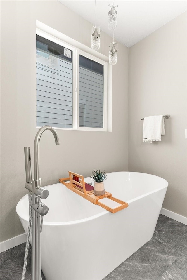 bathroom featuring a freestanding bath and baseboards