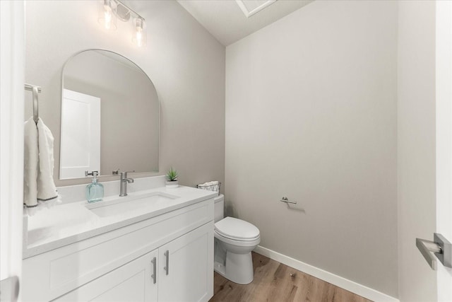 bathroom featuring baseboards, toilet, wood finished floors, and vanity