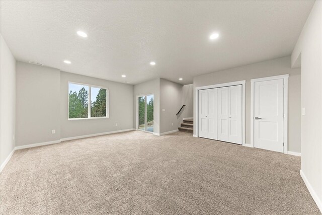 interior space featuring baseboards, carpet, stairway, recessed lighting, and a textured ceiling