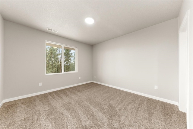 spare room featuring visible vents, a textured ceiling, baseboards, and carpet floors