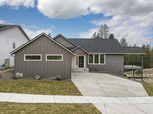 view of front of property featuring roof with shingles, board and batten siding, and a front lawn