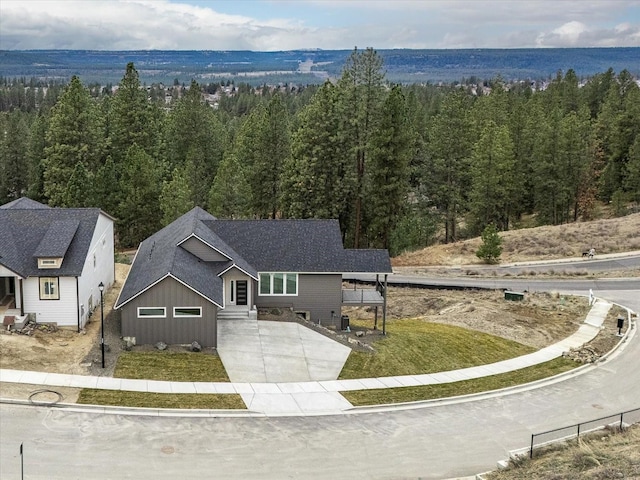 view of front of property with concrete driveway and a wooded view