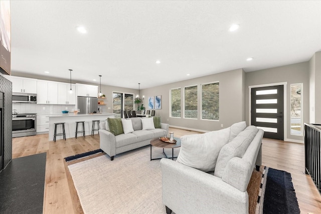 living room featuring recessed lighting, baseboards, and light wood-style floors