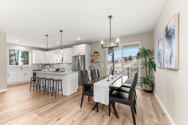 dining room with recessed lighting, a notable chandelier, baseboards, and light wood-style floors