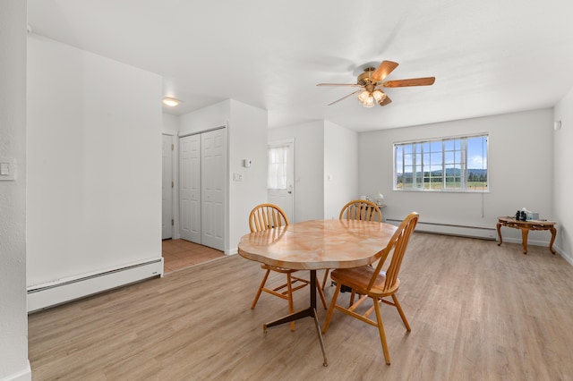 dining space with baseboards, light wood-style floors, and a baseboard radiator