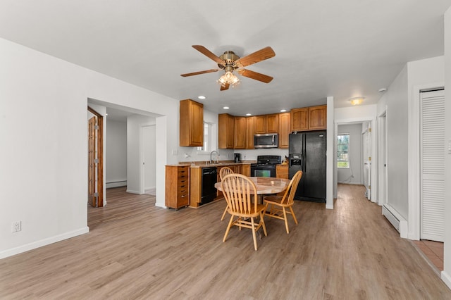 kitchen featuring light wood-type flooring, a baseboard heating unit, baseboard heating, and black appliances