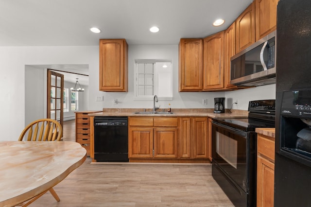 kitchen featuring black appliances, recessed lighting, light wood-type flooring, and a sink