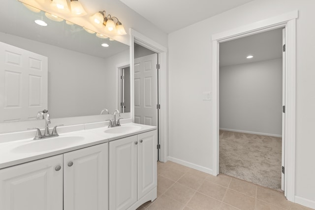 full bath with a sink, baseboards, double vanity, and tile patterned flooring