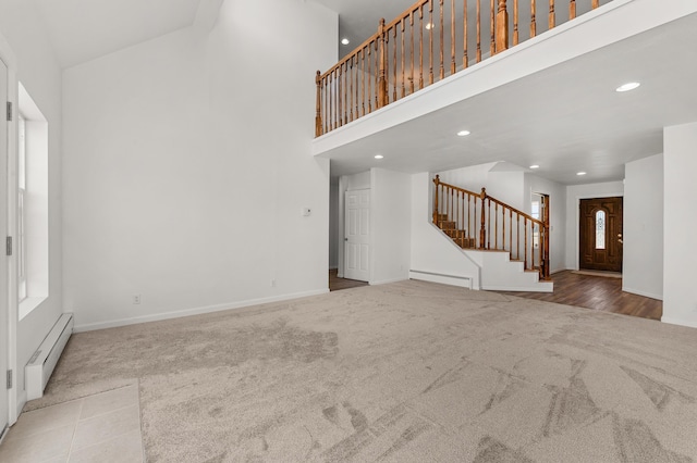 unfurnished living room with stairway, carpet floors, recessed lighting, a towering ceiling, and baseboard heating