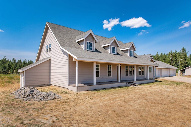 view of front of property with an outbuilding, a front lawn, a porch, roof with shingles, and a garage