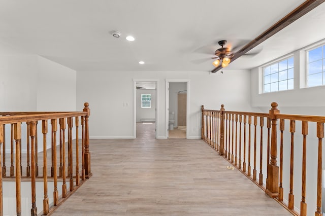 corridor featuring plenty of natural light, an upstairs landing, baseboards, and light wood finished floors