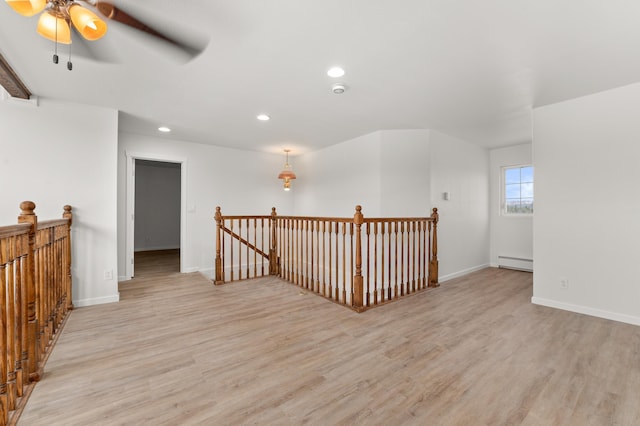 interior space with an upstairs landing, baseboards, light wood-style floors, and a baseboard radiator